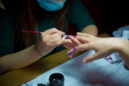 Manicure hands salon . Woman in a nail salon receiving a manicure by a beautician . Manicure process in beautiful salon . Closeup of Woman applying nail varnish to finger nailsの写真素材