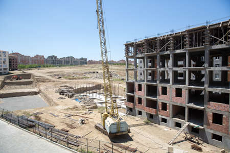 New building is being constructed with use of tower crane .Large construction site including several cranes working on a building complex, with clear blue sky .working on a construction siteの写真素材