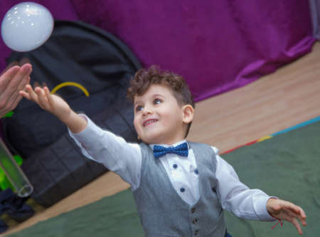 Azerbaijan Baku . 04.02.2020 .Cute little boy catching soap bubbles . Little blonde boy playing with soap bubbles . Children at the feast. Soap bubbles show. Children's party. To burst the soap bubbleのeditorial素材