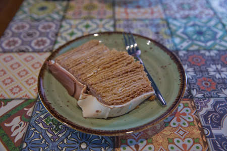 Cake and fork in a white plate on wooden background . White chopped cake wooden background inside a white plate. fork . Brown and white cake on wood board . Cake with biscuit and creamの写真素材