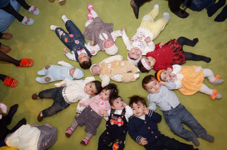 Group of cute children lying . Group of happy diversity looking kids laying in star shape on the floor . happy smiling children lying on floor in circle .のeditorial素材