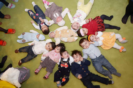 Azerbaijan Baku . 24.12.2010 . Group of eight happy diversity looking kids, boys and girls laying in star shape on the floor. Happy smiling children lying on floor in circle .のeditorial素材