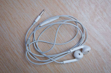 Earbud or earphone top view on wooden background . White earphones from the phoneの写真素材