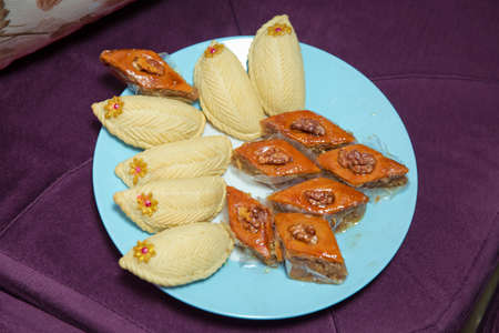 Baklava and Shekerbura blue plate purple background . Shekerbura with nuts and honey.の写真素材