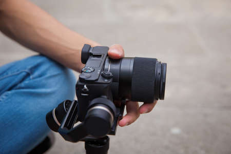 Gimbal Operator with black equipament - Stabilizer and camera filmmaking . An unidentified man holding gimbal a camera stabilizer . Man holding gimbal stabilizer outdoor.の写真素材