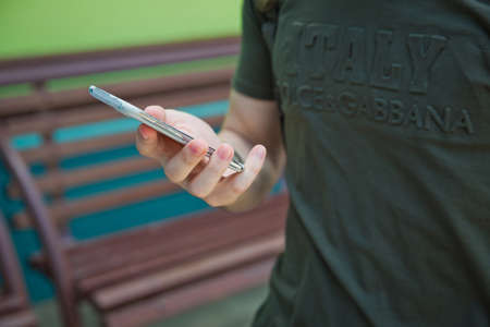 Boy holding telephone in hand . He has a white Samsung phone in his hand .のeditorial素材