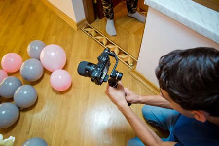 Man holding gimbal stabilizer outdoor. Gimbal Operator with black equipament - Stabilizer and camera filmmaking . An unidentified man holding gimbal a camera stabilizer .The camera shoots the balloonのeditorial素材