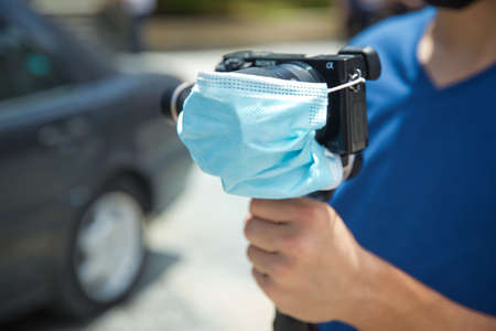 Azerbaijan Baku : 26.06.2020 . Man holding gimbal stabilizer camera outdoor. A blue mask is attached to the camera lens. The camera is protected by COVID-19の写真素材