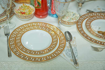 Empty plate , gold set on wooden white table . Beautifully decorated table with gold plates, linen napkin , spoon, fork .の写真素材