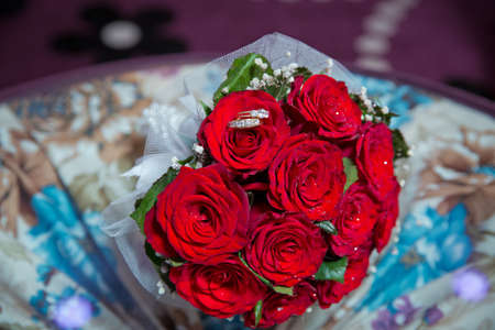 Rings on the wedding bouquet . Gold wedding rings on a bouquet of red gold flowers.の写真素材