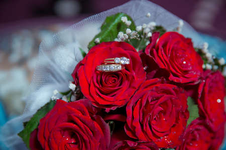 Rings on the wedding bouquet . Gold wedding rings on a bouquet of red gold flowers.の写真素材