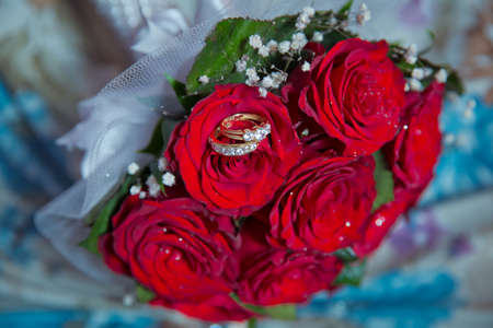 Rings on the wedding bouquet . Gold wedding rings on a bouquet of red gold flowers.の写真素材