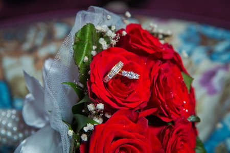 Rings on the wedding bouquet . Gold wedding rings on a bouquet of red gold flowers.の写真素材