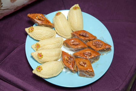 Shekerbura with nuts and honey. Baklava and Shekerbura blue plate purple background . Baklava and Shekerbura on a plate.の写真素材