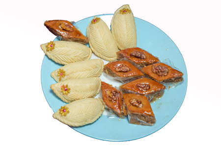 Shekerbura with nuts and honey. Baklava and Shekerbura blue plate purple background . Baklava and Shekerbura on a plate.の写真素材