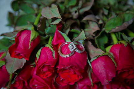 Rings on the wedding bouquet . Gold wedding rings on a bouquet of red gold flowers.の写真素材