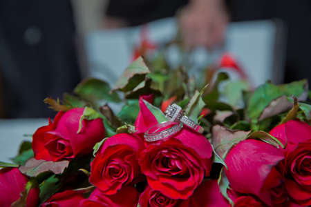 Rings on the wedding bouquet . Gold wedding rings on a bouquet of red gold flowers.の写真素材