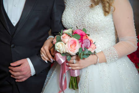 Close-up photo of bride standing next to her husband holds a bouquet in her hand outdoor . nice wedding bouquet in brides hand .の写真素材