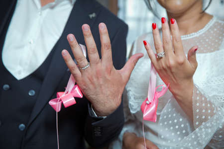 Happy couple show their hands with wedding rings. Bride and groom show their hands with wedding rings. Shallow depth of field . The bride and groom show the ring on their hands .の写真素材