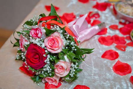 Rings on the wedding bouquet . The engagement rings are tied with ribbon Selective focus and blurred background . Gold wedding rings on a bouquet of red and white flowers.の写真素材