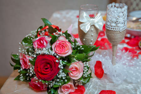 Rings on the wedding bouquet . The engagement rings are tied with ribbon Selective focus and blurred background . Gold wedding rings on a bouquet of red and white flowers.の写真素材