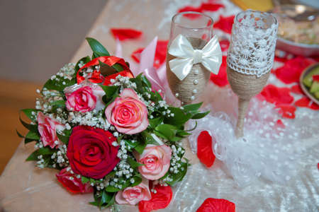 Rings on the wedding bouquet . The engagement rings are tied with ribbon Selective focus and blurred background . Gold wedding rings on a bouquet of red and white flowers.の写真素材