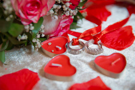 Red heart candles . Red rose petals . Gold wedding rings .の写真素材
