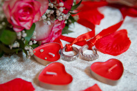 Red heart candles . Red rose petals . Gold wedding rings .の写真素材
