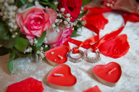 Red heart candles . Red rose petals . Gold wedding rings .の写真素材