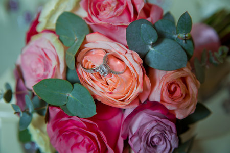 Gold rings for a wedding on a bouquet of flowers. peach wedding rose bouquet . Bouquet of orange roses.の写真素材