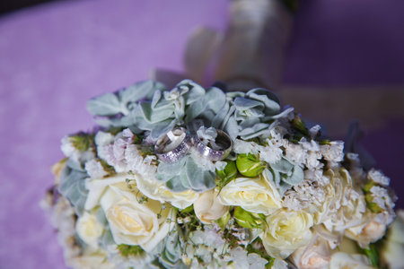 Gold rings for a wedding on a bouquet of flowers. White wedding rose bouquet . Bouquet of white roses.の写真素材