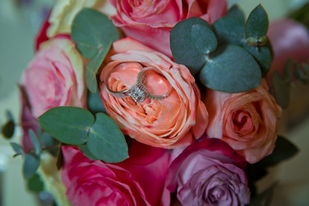 Gold rings for a wedding on a bouquet of flowers. peach wedding rose bouquet . Bouquet of orange roses.の写真素材