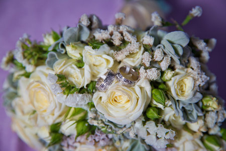 Gold rings for a wedding on a bouquet of flowers. White wedding rose bouquet . Bouquet of white roses.の写真素材