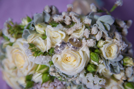 Gold rings for a wedding on a bouquet of flowers. White wedding rose bouquet . Bouquet of white roses.の写真素材