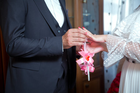 Newlyweds exchange rings, groom puts the ring on the brides hand in marriage registry office . The brides is wearing a ring on the brides hand . Engagement.The groom puts a ring on the brides hand.の写真素材