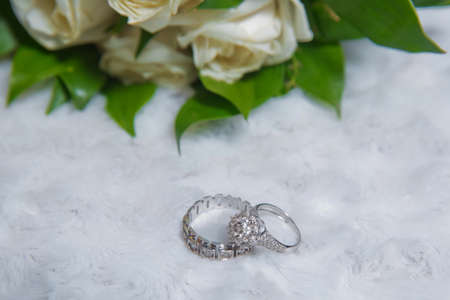 Stylish white wedding flower Rings in front of the wedding bouquet . Wedding engagement rings on the background of a beautiful bouquet of roses .の写真素材