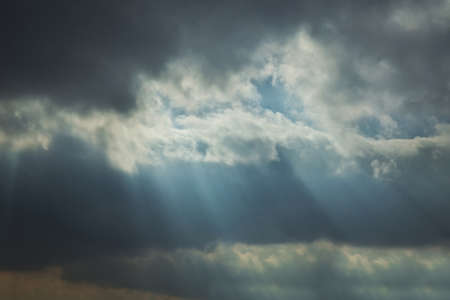the rays of the sun among the clouds of the sky . RAY OF SUNLIGHT ESCAPING AMONG THE CLOUDS . Sky with sun rays among the clouds.の写真素材