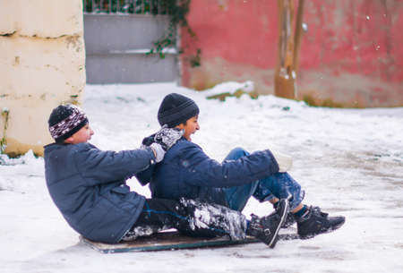 Boys sledding in a snowy . Children ski in the snow . The children were very happy and laughing ....