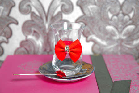 Black turkish tea in pear shape glass, aromatic tea in armudu cup . Tea in Azerbaijani traditional armudu pear-shaped glass . Filtered tea for engagement . closed with a red ribbon . check bow tieの写真素材