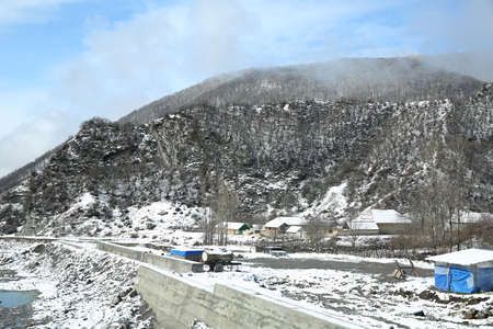 Concrete body in the river . Concrete walls to protect the village from strong floods. Winter and mountains . There is fog at the foot of the mountains . It snowed on the river stones .の写真素材