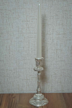 Beautiful candle on white background . Candle in candlestick burning . Retro Candelabra With Burning Candles . Burning Candle In Old Silver Candlestickの写真素材