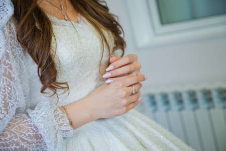 beautiful hands of the bride. Elegant female hands of bride in white dress . The bride wears a gold ring on her left hand with her right hand.の写真素材