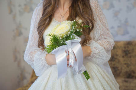 Delicate beautiful wedding bouquet of white roses in the hands of the bride at the wedding . Wedding bouquet in whiteの写真素材