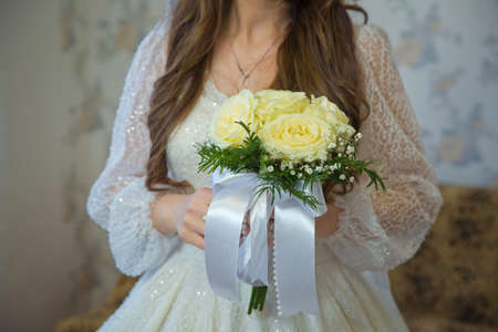 Delicate beautiful wedding bouquet of white roses in the hands of the bride at the wedding . Wedding bouquet in whiteの写真素材