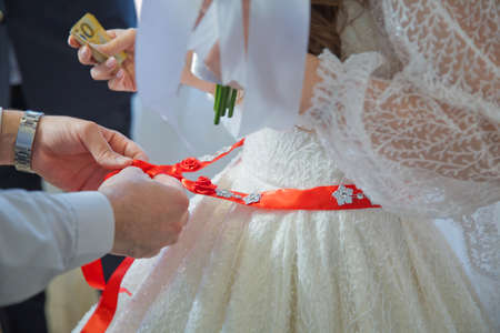 Close the ribbon on the belly of the bride . Bridesmaids lace bride . Close the ribbon on the belly the bride .の写真素材