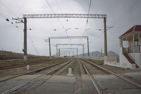 The local railway station on the rural area . Railway tracks turn to the left. Rails for the train, laid on a hill above the city, smoothly turn left. Technological background. Blue sky over the railrの写真素材