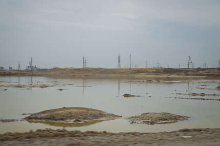 Desert Landscape with Transmission Towers . They laid the railway lines on top of each other. A small lake and oil rocks in the desert. The water in the pond has been drained.の写真素材