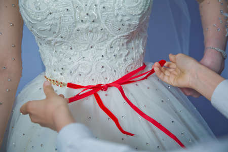 Lose the ribbon on the belly of the bride . Wedding . Bridesmaids lace bride . Close the ribbon on...