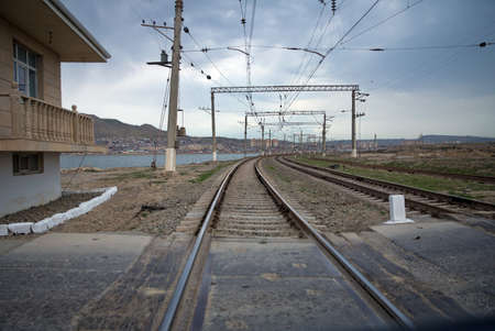 The local railway station on the rural area . Railway tracks turn to the left. Rails for the train, laid on a hill above the city, smoothly turn left. Technological background. Blue sky over the railrの写真素材