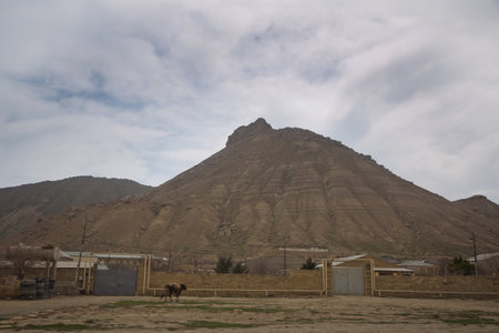 view of volcano . bare mountain and country houses in front . There are rocks at the top of the mountainの写真素材